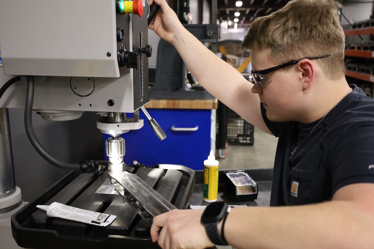 Apprentice student pressing metal