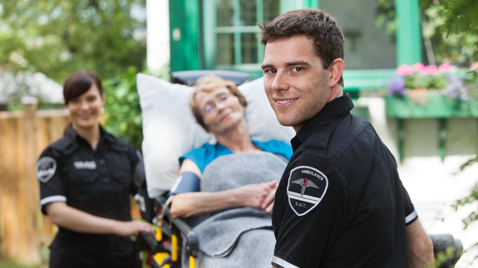 Two EMTs service an elderly patient on a stretcher